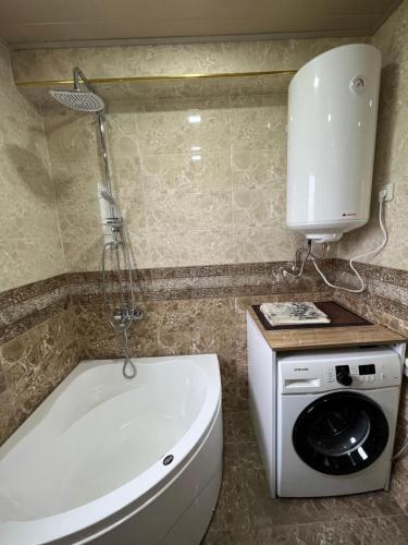 a bathroom with a tub and a toilet and a washing machine at Mountain KAZBEGI Apartment in Stepantsminda