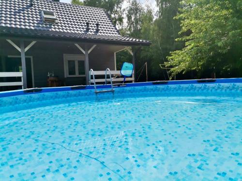 a large swimming pool with a chair and a house at Dziki zakątek Piskornia dom z balią jacuzzi in Piskornia