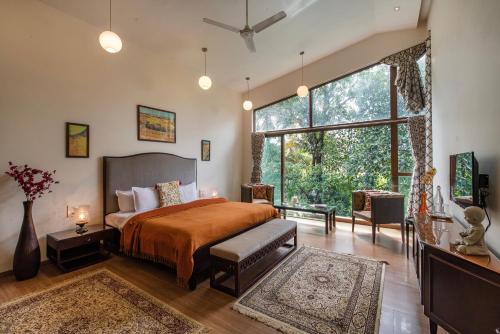 a bedroom with a bed and a large window at SaffronStays Miraya - Nature Retreat, Pool, Games, Bar in Alibaug in Alibaug