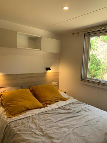 1 cama con almohadas amarillas en una habitación con ventana en Le Domaine des Pins, en Saint-Hilaire-de-Riez
