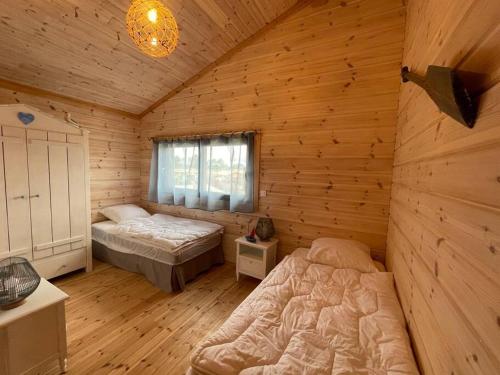 Un dormitorio con dos camas en una cabaña de madera. en Superbe maison finlandaise en bois, en Tosse