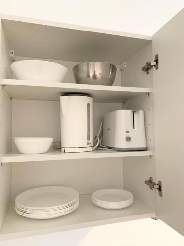 une cuisine avec des étagères blanches avec des bols et des appareils électroménagers dans l'établissement Le nid troyens, à Troyes