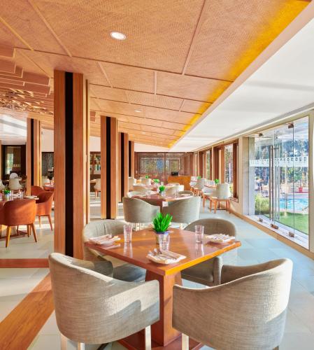 a dining room with tables and chairs and windows at The Resort in Mumbai