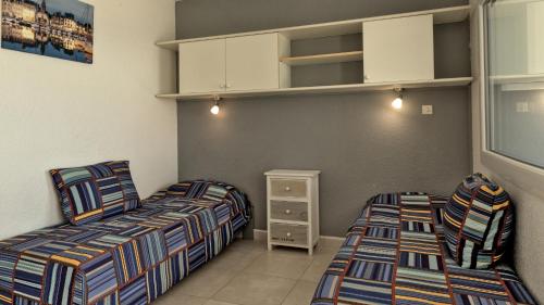 a bedroom with two beds and a cabinet at Residence Ulysse Port Camargue in Le Grau-du-Roi
