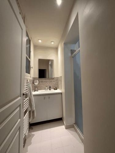 Charmant Appartement Parisien في باريس: حمام أبيض مع حوض ومرآة