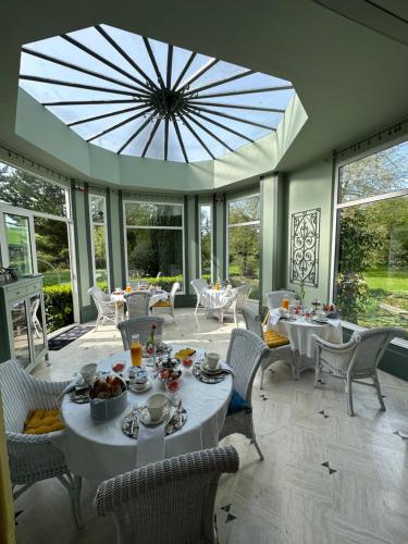 a dining room with white tables and chairs and a large window at Le Moulin de Francueil in Francueil