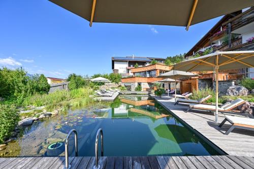 an outdoor swimming pool with a deck and a house at Biohotel Eggensberger in Füssen
