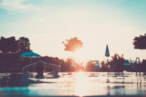 a person in the water with the sun in the background at Gasthof Martinhof in Sankt Martin im Sulmtal