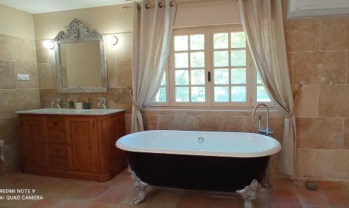 baño con bañera, lavabo y ventana en Le Mas Neuf 1752 en Arlés