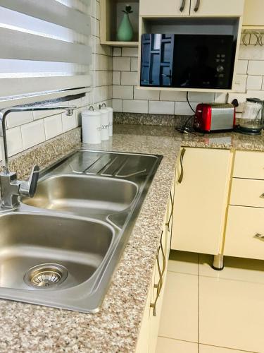 a kitchen with a sink and a microwave at Mjejane Debs guest house in Hectorspruit