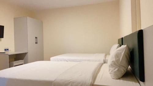a white bedroom with two beds and a cabinet at Hung Vuong Hotel in Pleiku