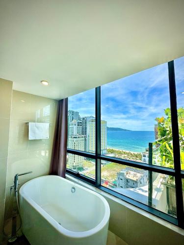 a bath tub in a bathroom with a large window at Avatar Danang Hotel in Da Nang