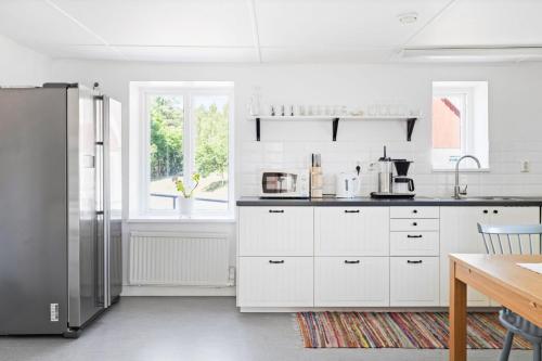 uma cozinha com armários brancos e um frigorífico em Jocksborg - Country side cottage in the woods em Sjöbo