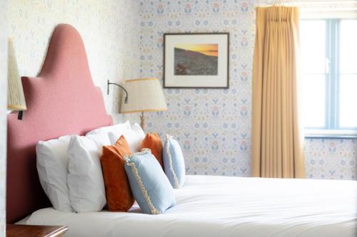 a bedroom with a white bed with a pink headboard at The Barnsdale, Rutland in Oakham
