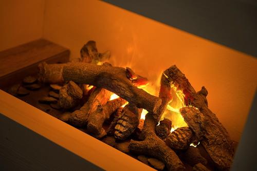 a fire inside of a fireplace with some logs at Sporthotel Rosatti in Dimaro