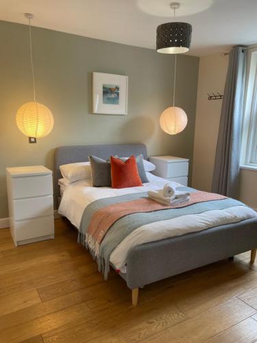 a bedroom with a bed with red pillows and two lamps at Town Centre, 2 x Double bedroom apartment with smart TV, full kitchen & great 1400 power shower! in Dartmouth