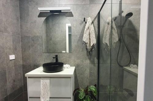 a bathroom with a sink and a mirror and a shower at Ballarat Holiday Homes - Hopetoun Cottage - Minutes from Ballarat CBD - Sleeps 1 to 6 in Ballarat