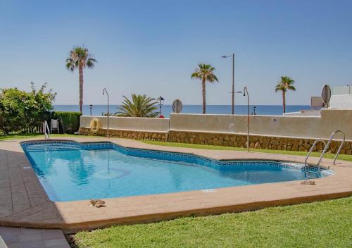 a swimming pool with palm trees and the ocean in the background at Apto Julia, 1ª Línea de Playa y Vistas al Mar in Mojácar