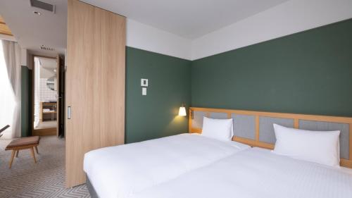 a bedroom with two beds and a green wall at RAKURO Kyoto by THE SHARE HOTELS in Kyoto