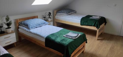 a bedroom with two beds with green sheets at Zielony Zakątek - agroturystyka blisko morza in Kierzkowo