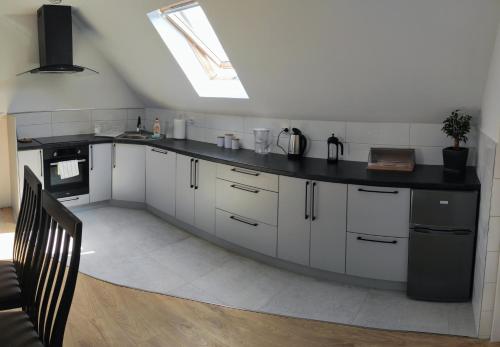 a kitchen with white cabinets and a black counter top at Zielony Zakątek - agroturystyka blisko morza in Kierzkowo