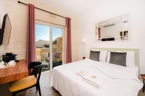 a bedroom with a bed and a desk and a window at Battistini Boutique Living Hotel and Spa, Victoria, Gozo in Victoria