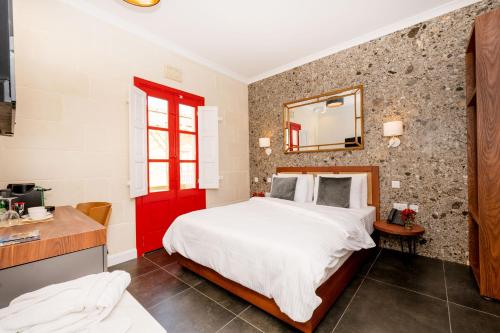 a bedroom with a large bed and a red door at Battistini Boutique Living and Spa, Victoria, Gozo in Victoria