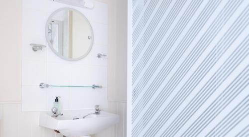 a white bathroom with a sink and a mirror at Coniston in Sawrey