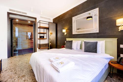a bedroom with a large white bed and a bathroom at Battistini Boutique Living and Spa, Victoria, Gozo in Victoria