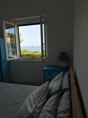 a bedroom with a bed and a window with a view at Cataleya Baia del Carpino Scalea in Scalea