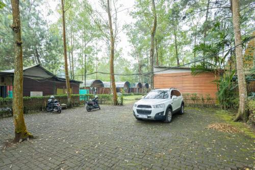 a car parked in a parking lot next to a fence at Chikar Glamping At Wisata Coban Talun Mitra RedDoorz in Junggo
