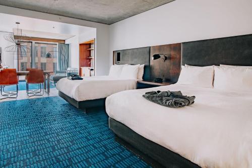 a hotel room with two beds and a dining area at The Maven Hotel at Dairy Block in Denver