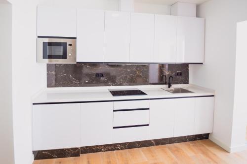 a white kitchen with a sink and a microwave at LUZ DE PATIOS in Huelva