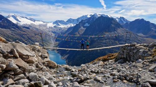 two people standing on a suspension bridge over a mountain lake at Haus Franka in Zellberg