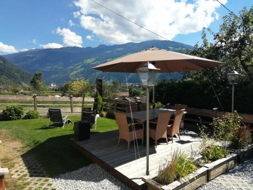 a wooden deck with a table and an umbrella at Haus Franka in Zellberg