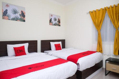 two beds in a room with red and white sheets at RedDoorz near Kawasan Bandara Ahmad Yani Semarang 2 in Kalibanteng-kidul
