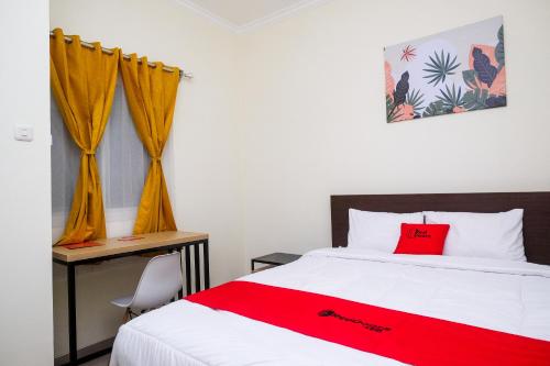 a bedroom with a red blanket on a bed at RedDoorz near Kawasan Bandara Ahmad Yani Semarang 2 in Kalibanteng-kidul