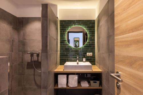 ein Bad mit einem Waschbecken und einem Spiegel in der Unterkunft Hotel Baumann in Otterfing