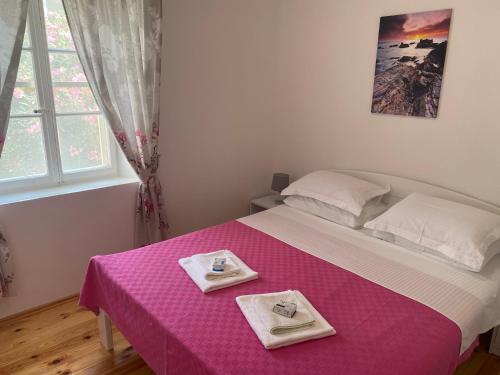 a bedroom with a pink bed with two plates on it at Apartment Lana in Tivat