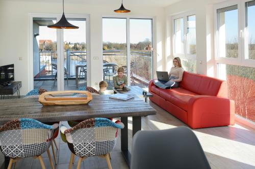 a woman and two children sitting in a living room at Havel-Spitze Ferienwohnungen in Brandenburg an der Havel