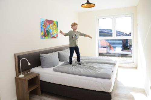 a young boy standing on top of a bed at Havel-Spitze Ferienwohnungen in Brandenburg an der Havel