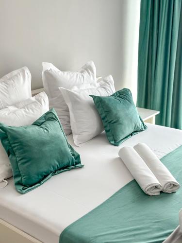 a white bed with green and white pillows on it at House Lake in Techirghiol