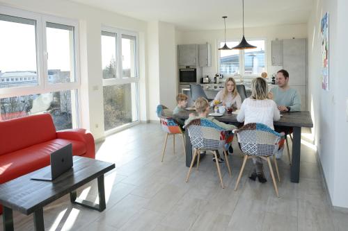 a family sitting at a table in a living room at Havel-Spitze Ferienwohnungen in Brandenburg an der Havel
