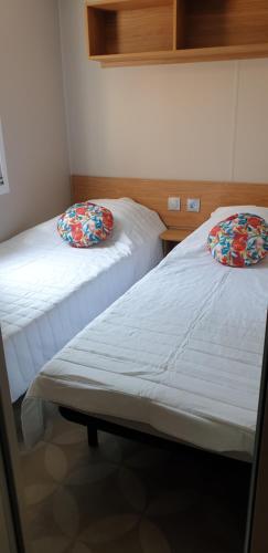 Dos camas una al lado de la otra en una habitación. en camping les sables du midi, en Sérignan