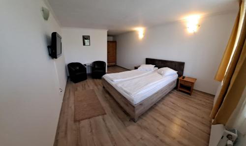 1 dormitorio con cama blanca y suelo de madera en Casa Dobric, en Sovata