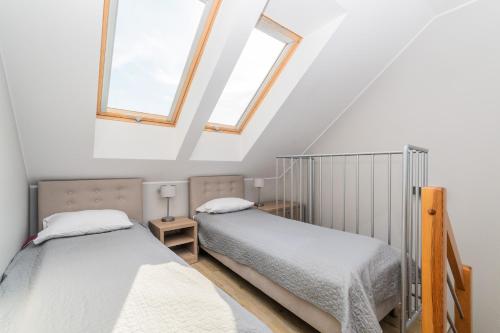 two beds in a room with two windows at APARTAMENTY MIERZEJA - STEGNA FOREST, Klimatyzacja, Przyjazne Zwierzętom, Bezpłatny Meleks in Stegna
