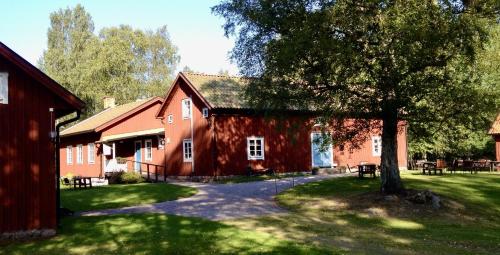 Um celeiro vermelho com uma árvore à frente. em Skagagården, Sjömarken em Undenäs