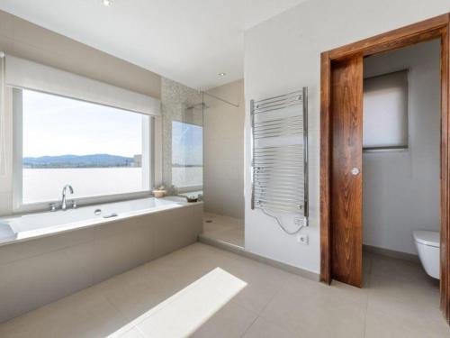 ein Badezimmer mit Badewanne und Toilette und einem Fenster in der Unterkunft Moderna casa con piscina privada in Santa Eulària des Riu