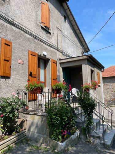 a house with wooden shutters and flowers in front of it at Casa Vacanze Ca' di Lucchini in San Benedetto Val di Sambro