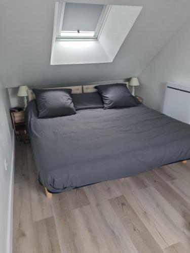 ein Bett mit schwarzen Kissen in einem Zimmer mit Fenster in der Unterkunft La Lande Chauvin in La Chapelle-Saint-Aubert